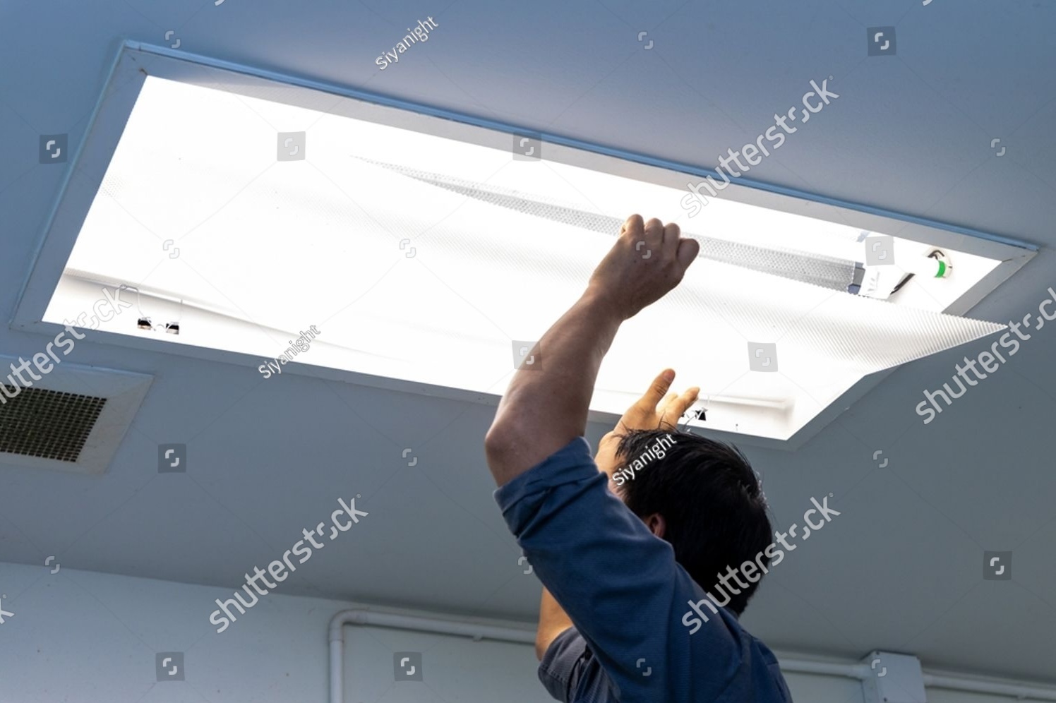 Technician installing a recessed luminaire